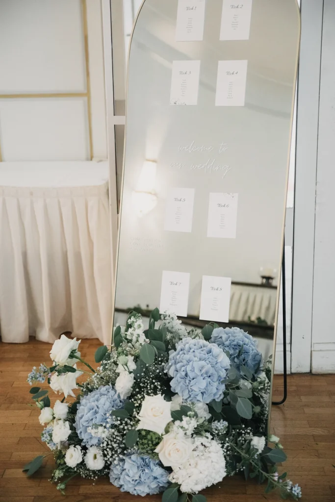 Weiße Tischkarten und hellblauer Blumenschmuck als Teil der Hochzeitsdekoration