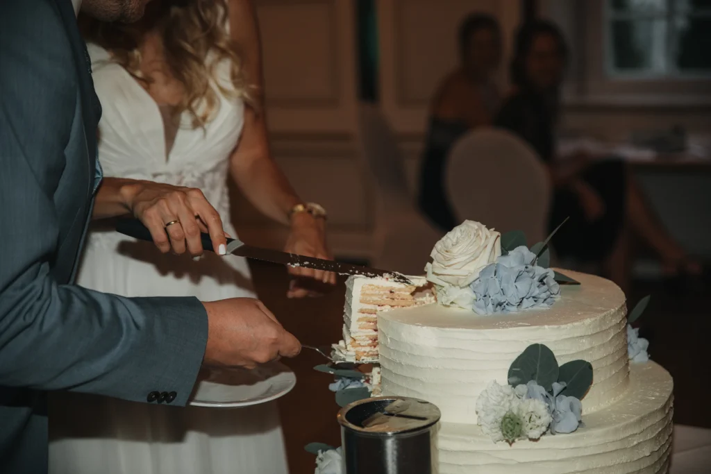 Ein Stück wird aus der mehrstöckigen Hochzeitstorte herausgeschnitten