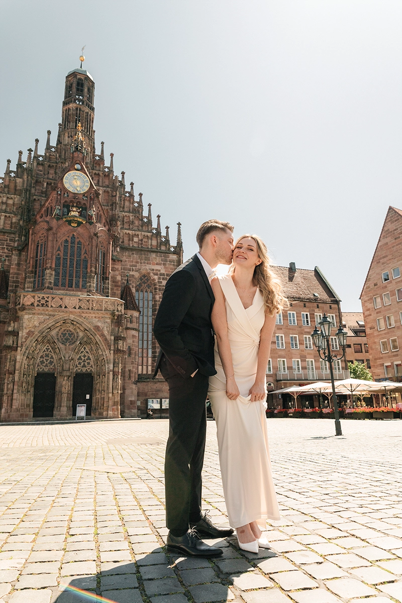 Brautpaar küsst sich auf dem Nürnberger Hauptmarkt mit der Frauenkirche im Hintergrund.