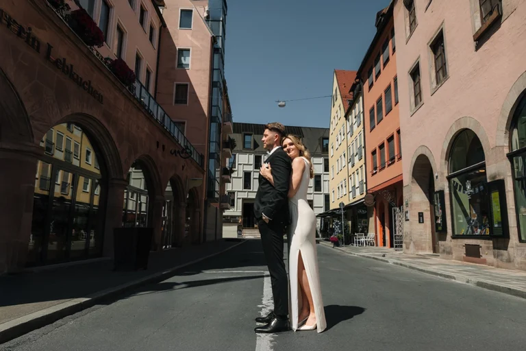 Braut und Bräutigam stehen nach ihrer standesamtlichen Trauung in einer sonnigen Straße der Nürnberger Altstadt.