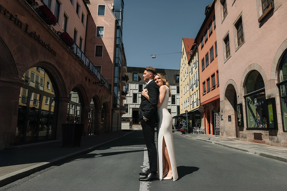 Braut und Bräutigam stehen nach ihrer standesamtlichen Trauung in einer sonnigen Straße der Nürnberger Altstadt.