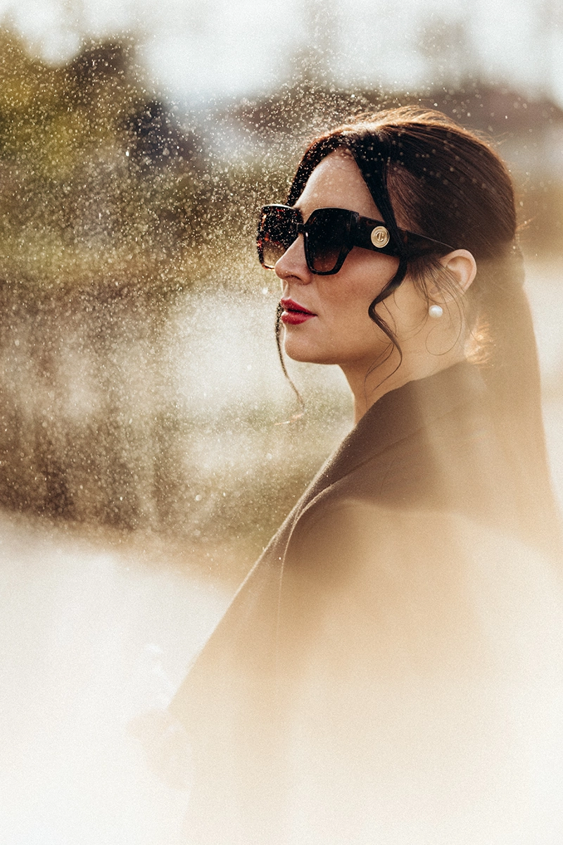 Elegantes Outdoor-Portrait einer Frau mit Sonnenbrille im Gegenlicht