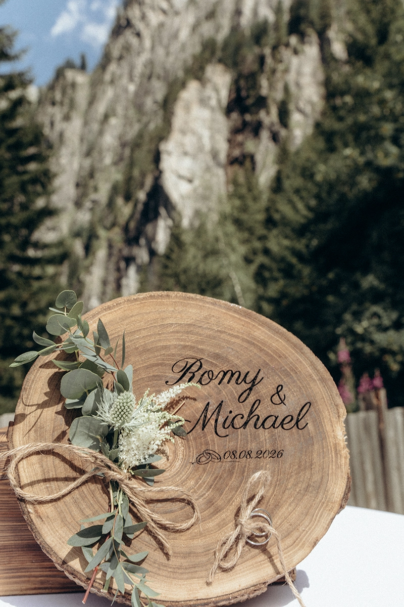 Die Eheringe von Romy und Michael auf einer gravierten Holzscheibe