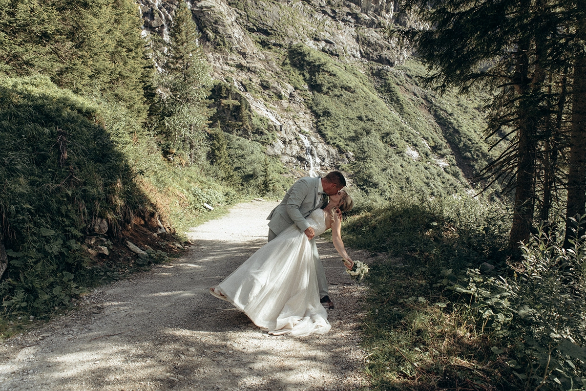 Das Hochzeitspaar geht gemeinsam über einen Weg durch die Berglandschaft.