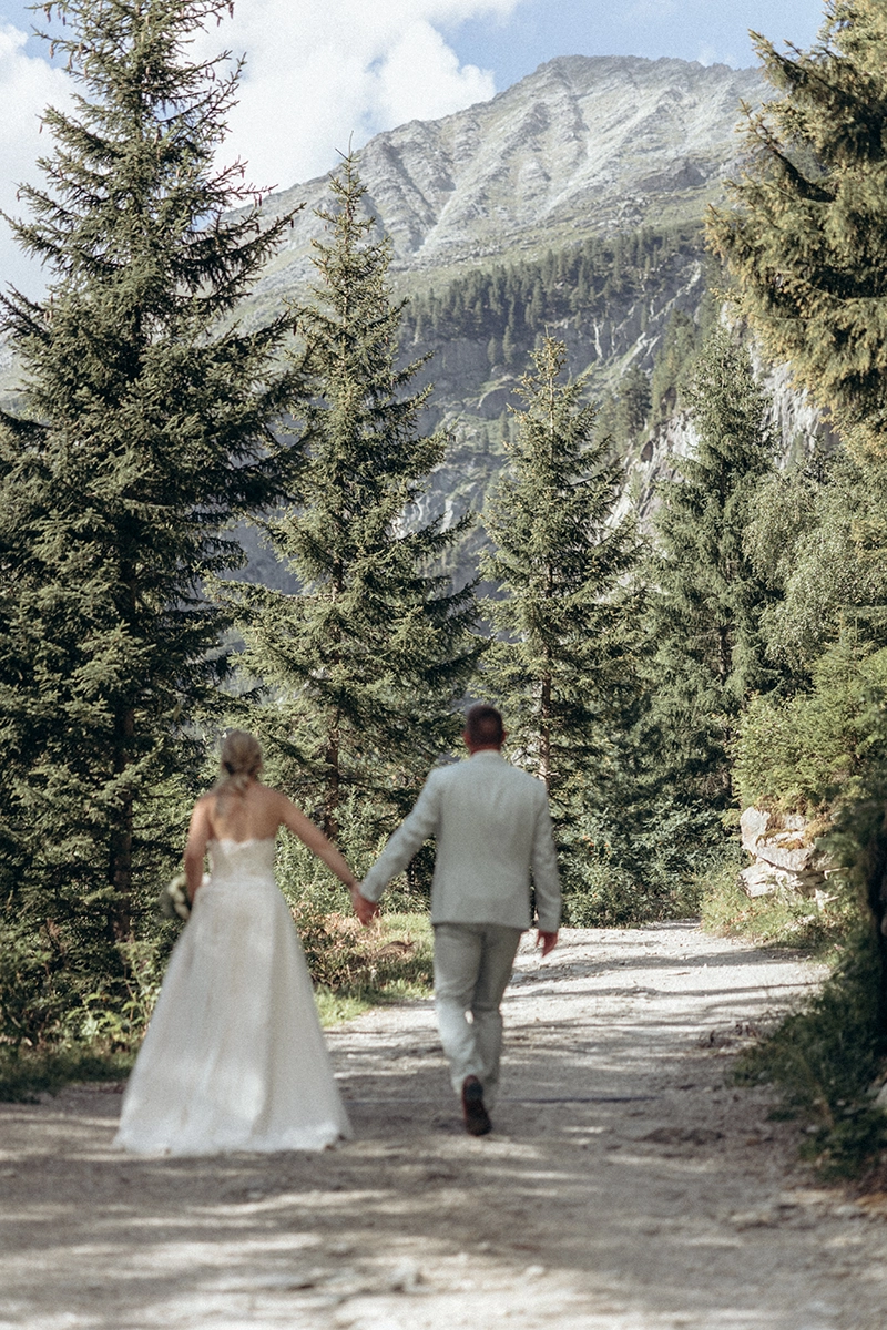 Das Brautpaar geht Hand in Hand über einen Bergweg im Zillertal.